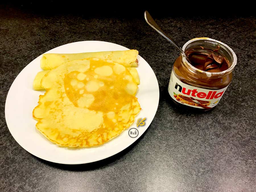 Bezlepkové palačinky na talíři s nutelou po pravé straně s vloženou lžící na kuchyňské lince | Bezlepkové palačinky | Bezlepkové recepty Rady ze života | Autor fotografie: Jiří Samuel | Recept: Tereza Samuelová