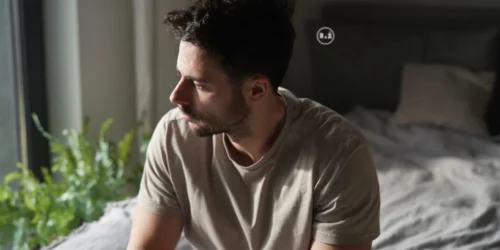 Mladý muž s natočenou hlavou do strany z profilu se zamyšlenou náladou spíše nešťastným pohledem do strany sedící v ložnici na posteli po levé straně okno za zády muže postel s polštáři | Pro článek: Jak na depresi? | Pro web: radyzezivota.cz | Zdroj: shutterstock.com