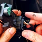 V rukách držím základnu se žárovkami pro zadní světla automobilu Volkswagen Sharan a naznačuji jak je možné uvolnit svorku s elektrickým kabelem pro článek: Výměna žárovky zadních světel, autor: Jiří Samuel, pro web: radyzezivota.cz