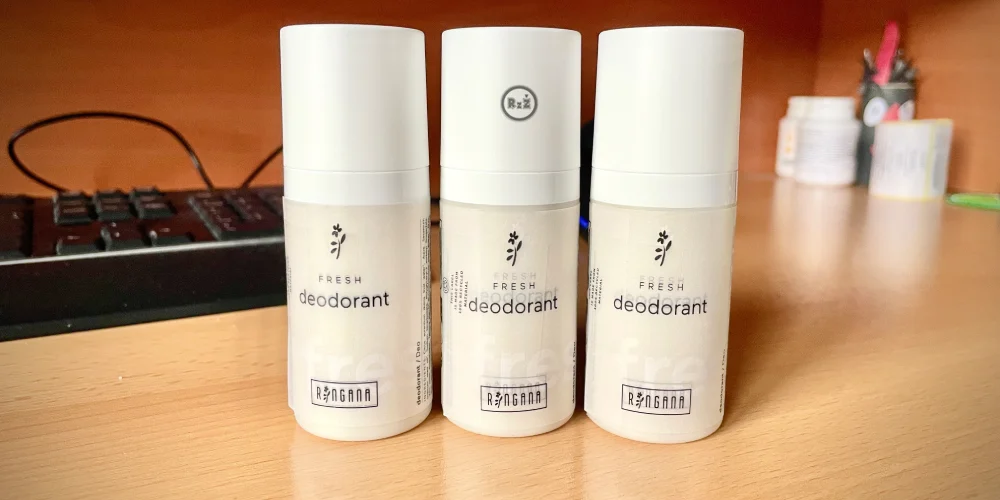 3 tekuté deodoranty vedle sebe s rozmazaným pozadím na kancelářském stole s tiskárnou a dalšími věcmi na dřevěném stole bez vylepšování - nejlepší na trhu rakouské značky Ringana