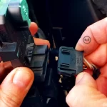 V rukách držím základnu se žárovkami pro zadní světla automobilu Volkswagen Sharan a naznačuji jak je možné uvolnit svorku s elektrickým kabelem pro článek: Výměna žárovky zadních světel, autor: Jiří Samuel, pro web: radyzezivota.cz