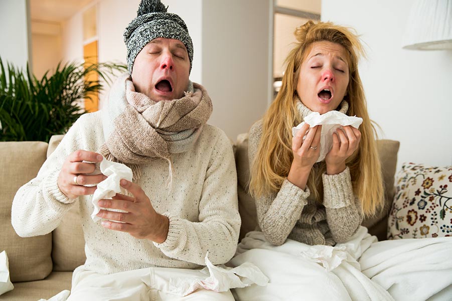 Ilustrativní foto pro článek Zadní rýma - příčina respiračních onemocnění | Žena a muž sedící doma nachlazení - v rukou drží bílé kapesníky majíc červené nosy - mají rýmu a nevypadají vůbec dobře (Zdroj: shutterstock.com)