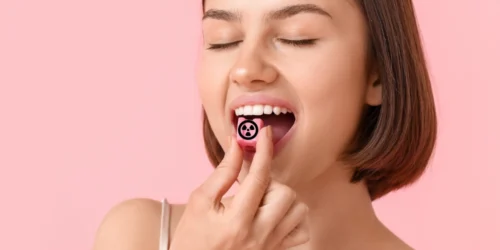 Mladá žena strkající žvýkačku s nebezpečným symbolem do úst v pozadí růžová barva | Pro web: radyzezivota.cz | Zdroj: shutterstock.com