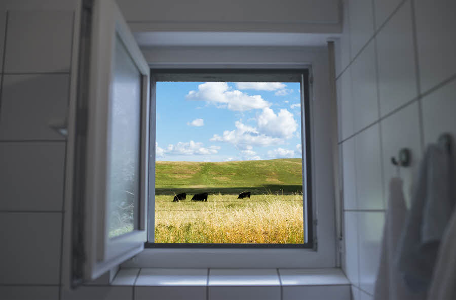 Fotografie otevřeného okna v koupelně s pozadím přírody